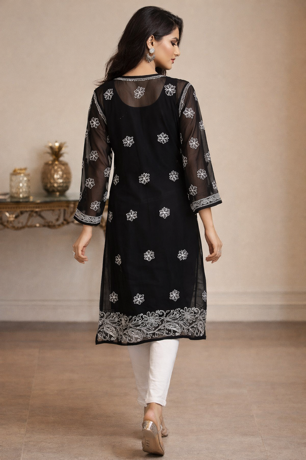 Woman wearing a black embroidered kurta with white pants in an indoor setting.