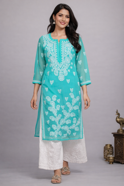 Woman wearing a turquoise embroidered kurta with white pants on a gray background