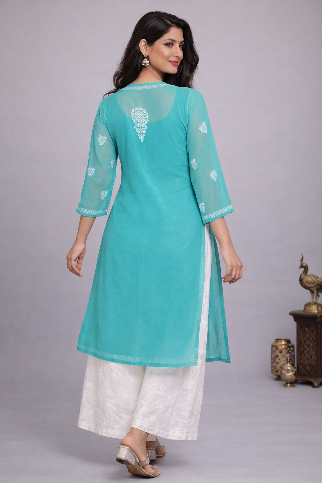 Woman wearing a turquoise and white traditional outfit on a gray background