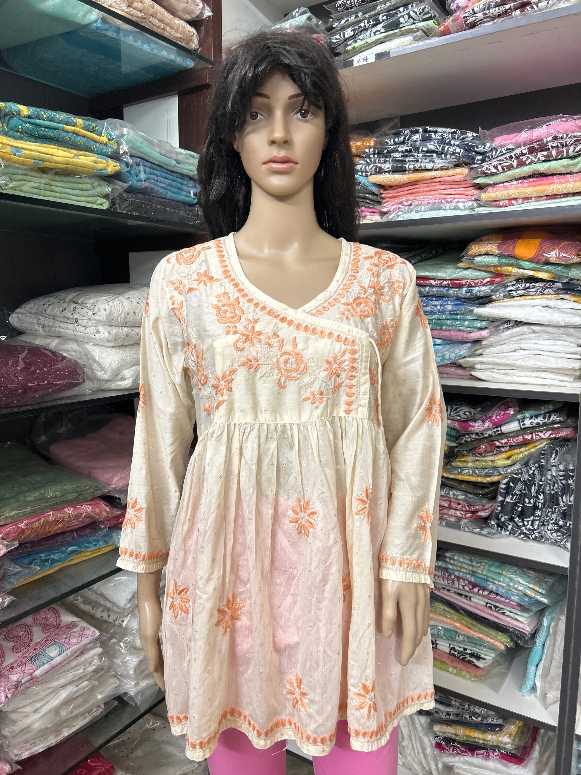 Mannequin wearing a cream-colored embroidered dress in a fabric store.