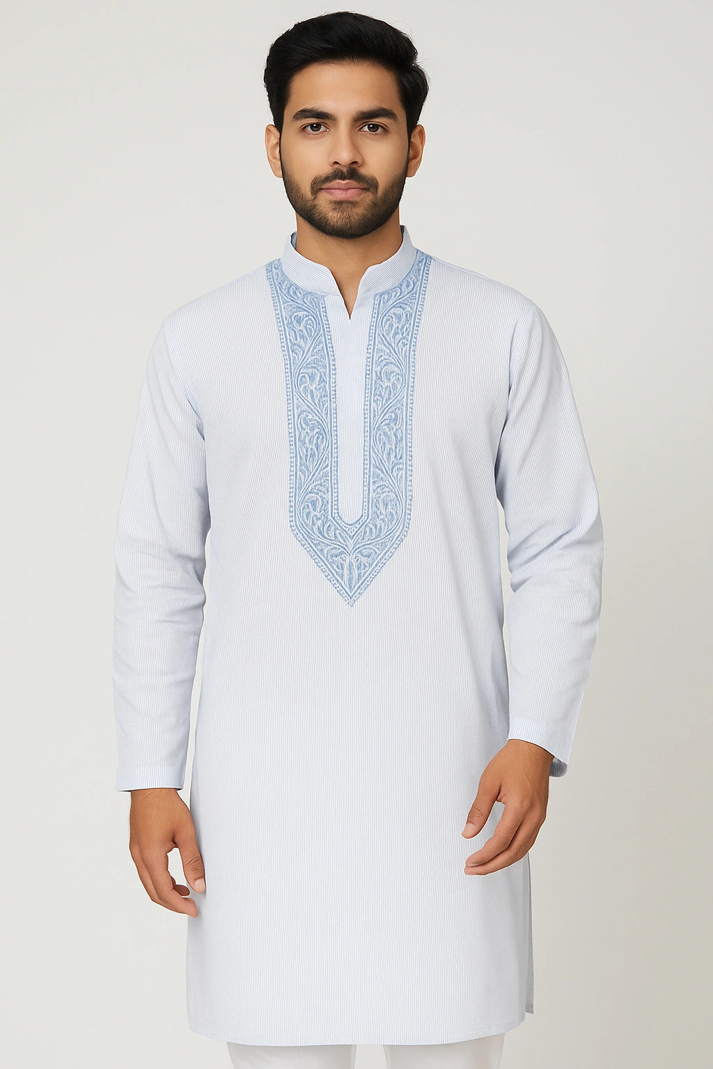 Man wearing a white kurta with blue embroidery on a light gray background