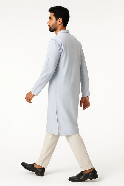 Man wearing a lucknowi chikankari light blue kurta with white pants on a white background