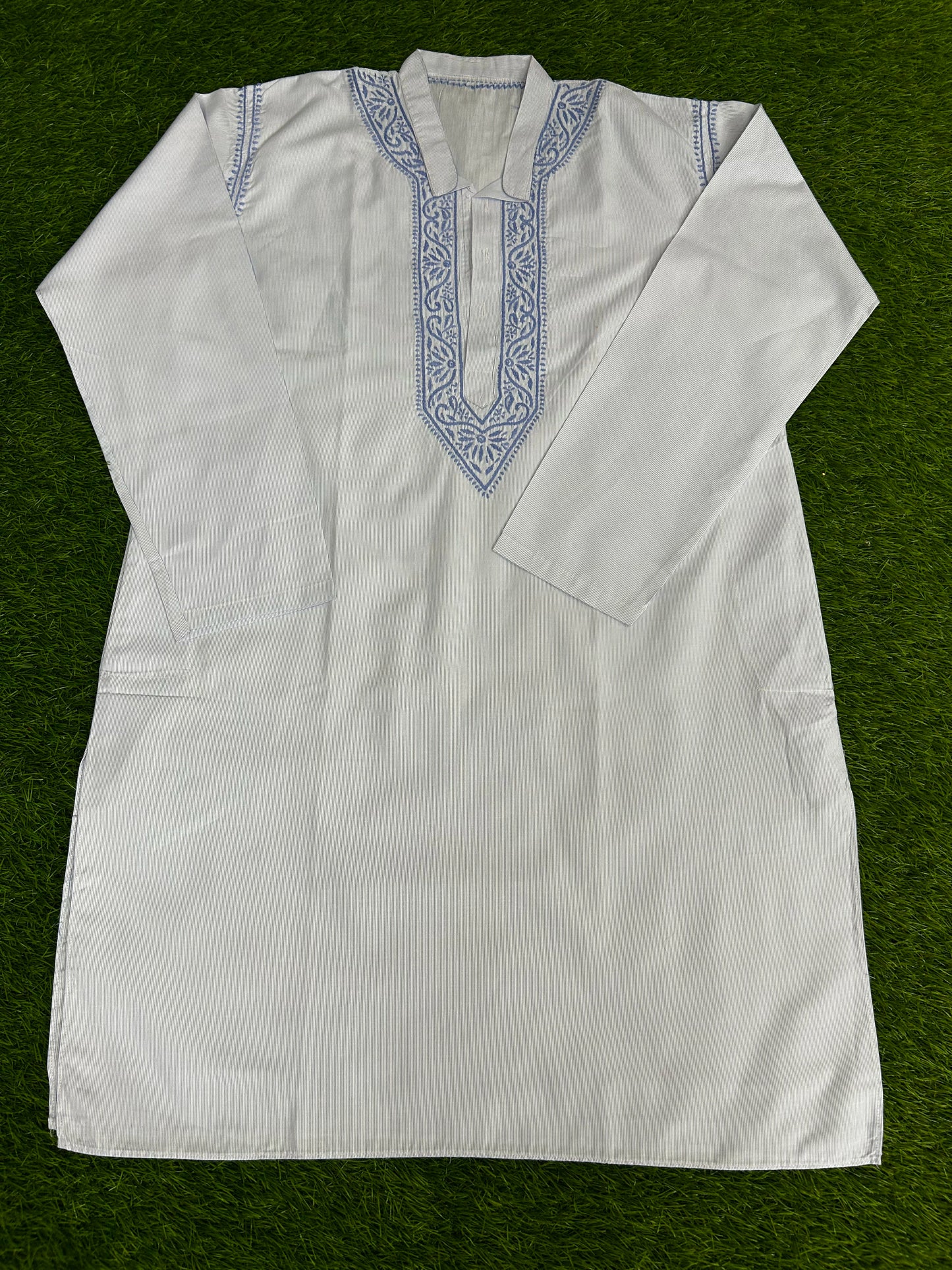 White embroidered shirt on a green background