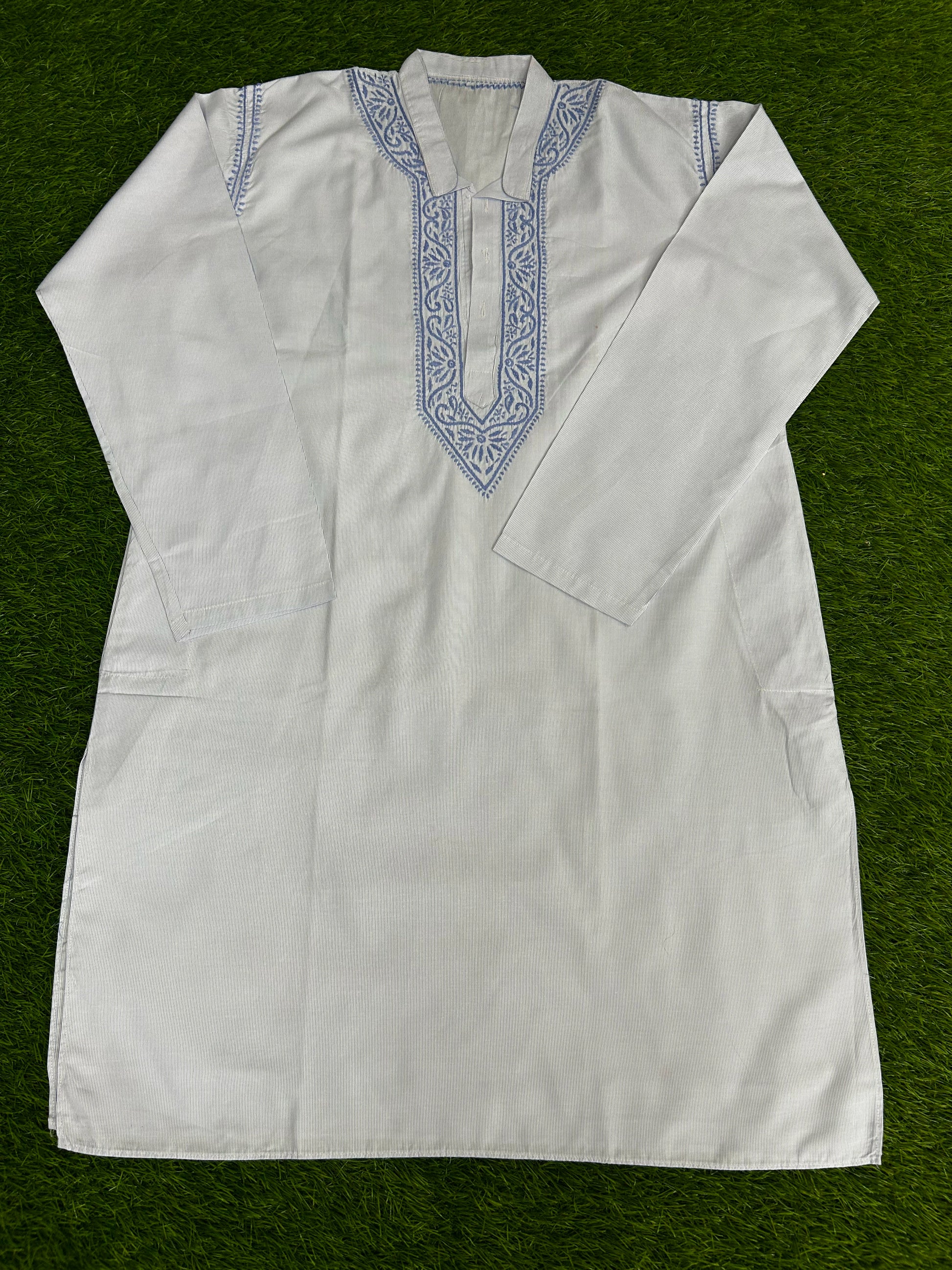 White embroidered shirt on a green background
