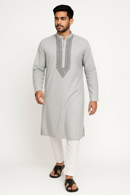 Man wearing a lucknowi chikankari light gray kurta with white pants on a white background