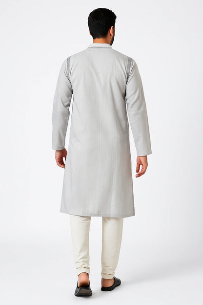 Man wearing a lucknowi chikankari light gray kurta with white pants on a white background