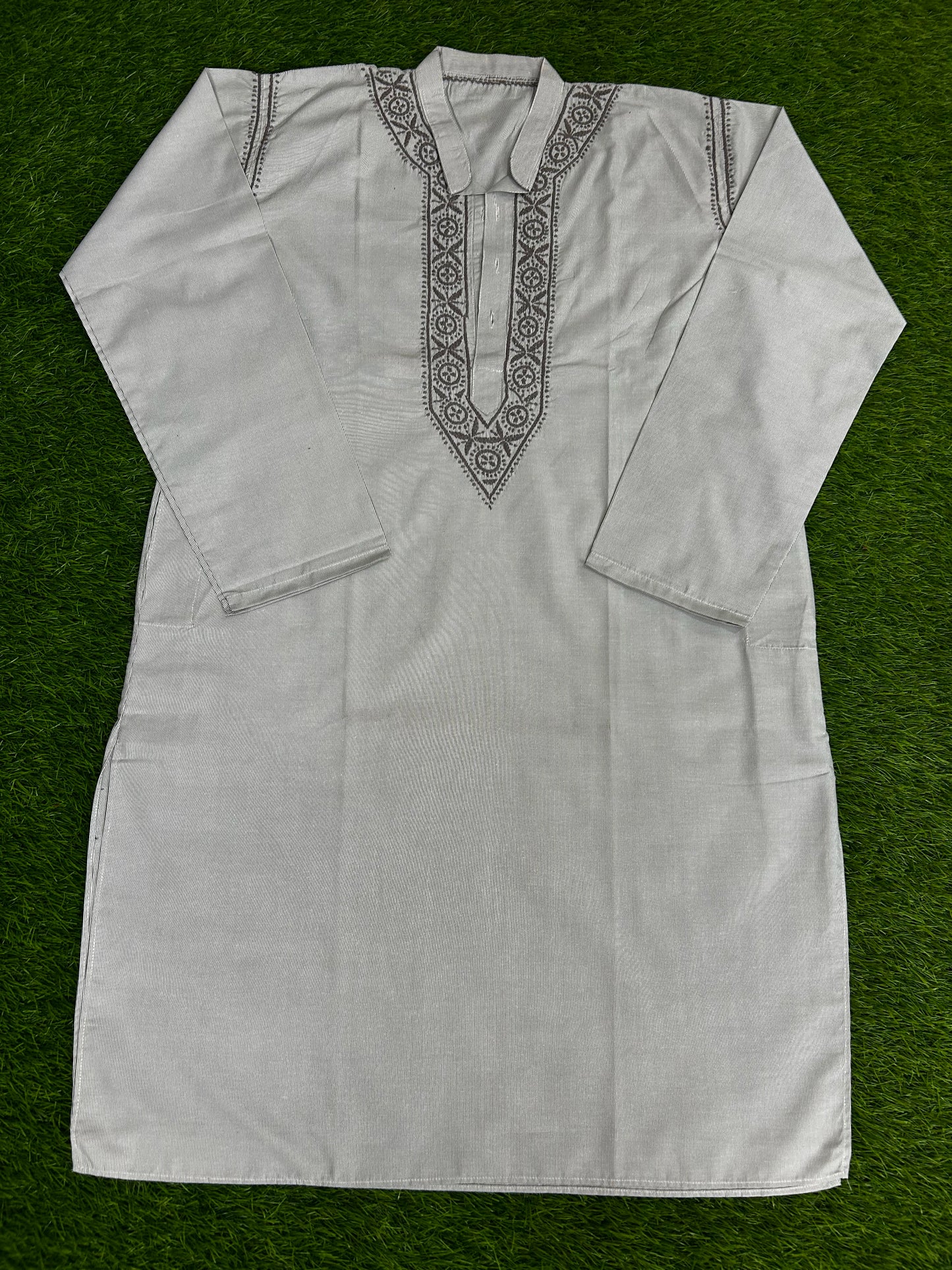White embroidered shirt on a green background