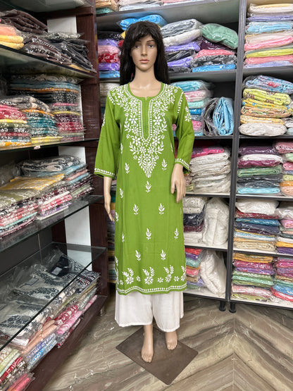 Mannequin wearing a lucknowi chikankari floral dress in a fabric store with shelves of fabric in the background.