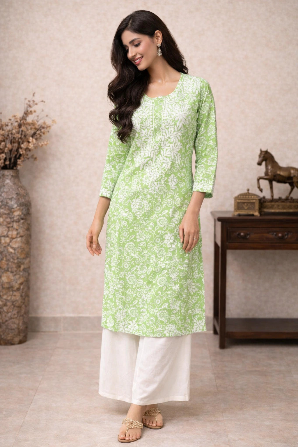 Woman wearing a light green kurta with white floral patterns and white pants indoors.