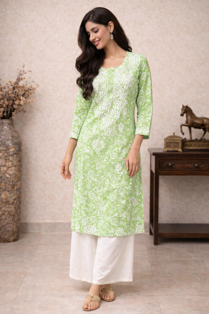 Woman wearing a light green kurta with white floral patterns and white pants indoors.