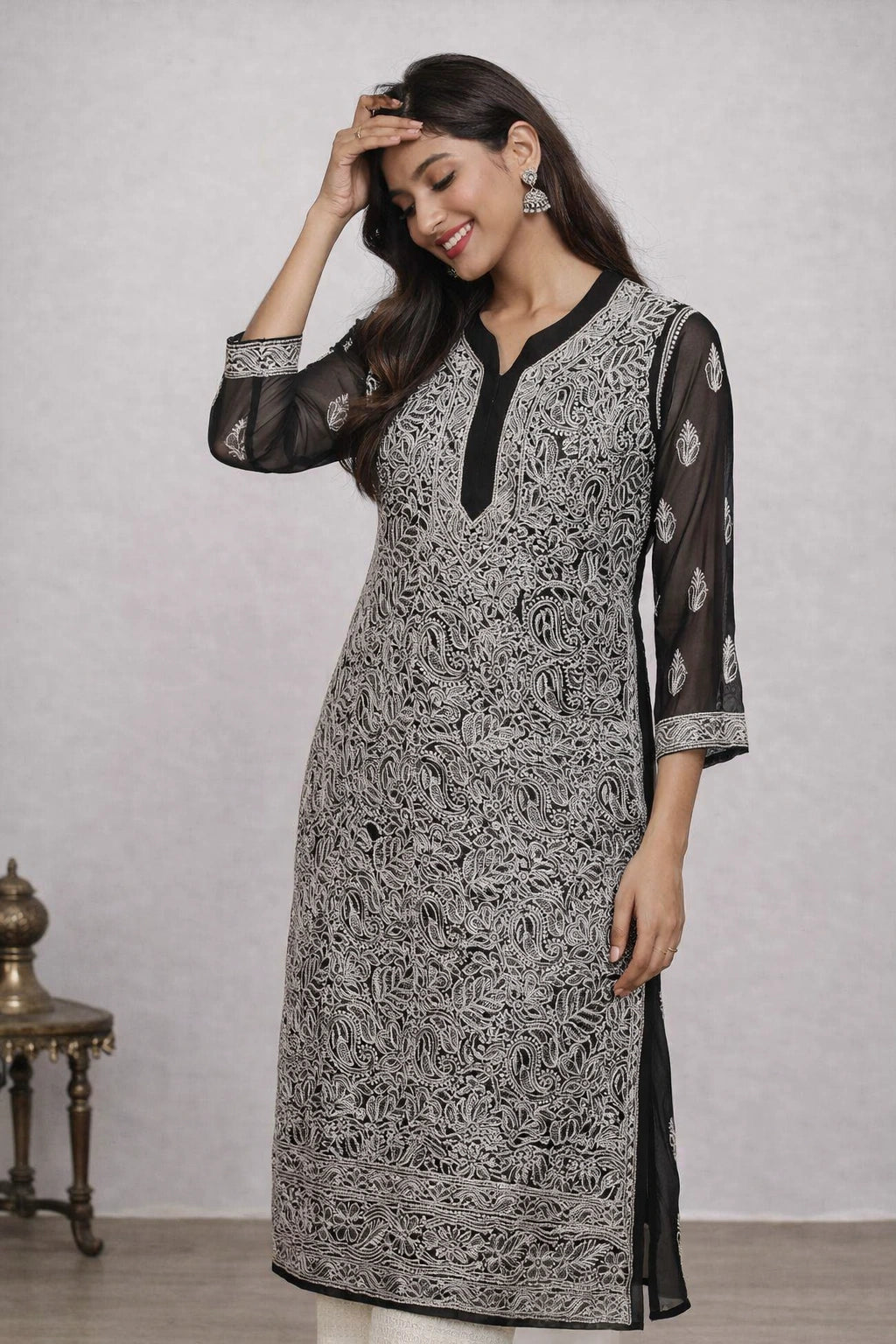Woman wearing a black and white patterned kurta with sheer sleeves against a plain background