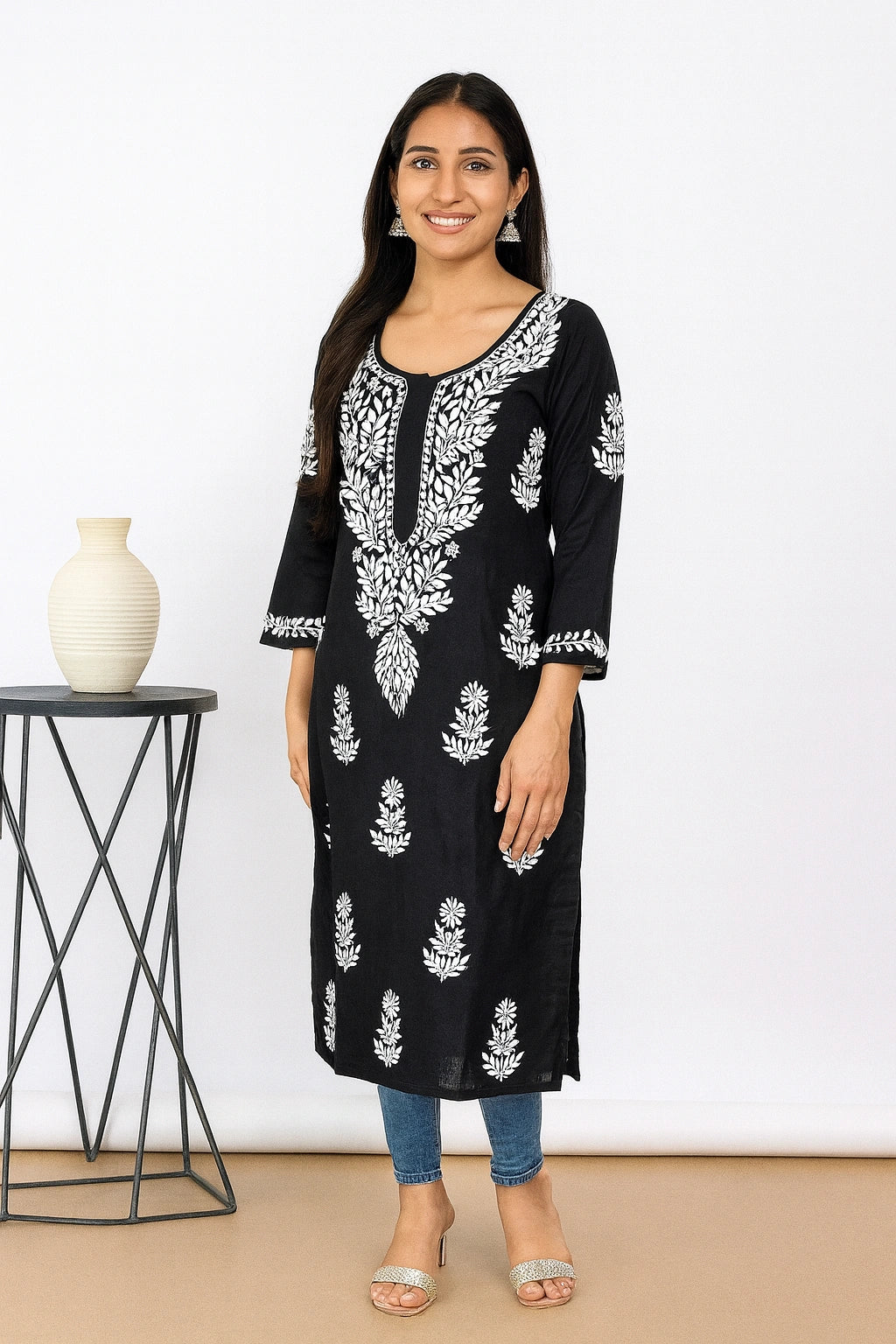 Woman wearing a black and red embroidered kurta with red pants against a white background