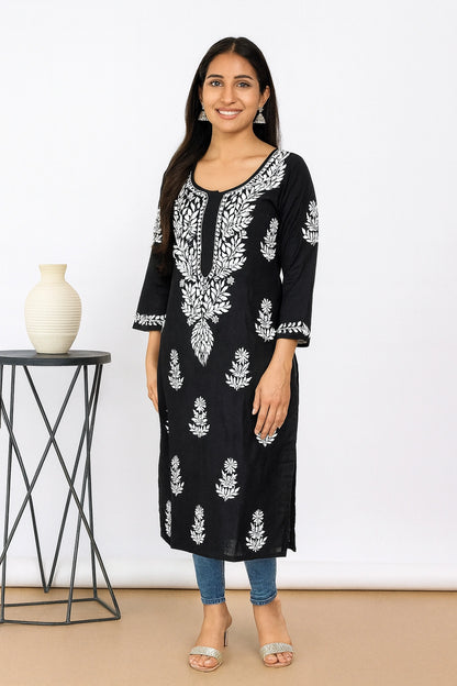Woman wearing a black and red embroidered kurta with red pants against a white background