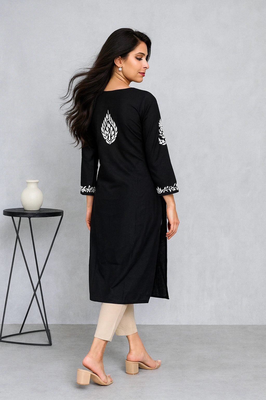 Woman wearing a black kurta with red details against a plain background