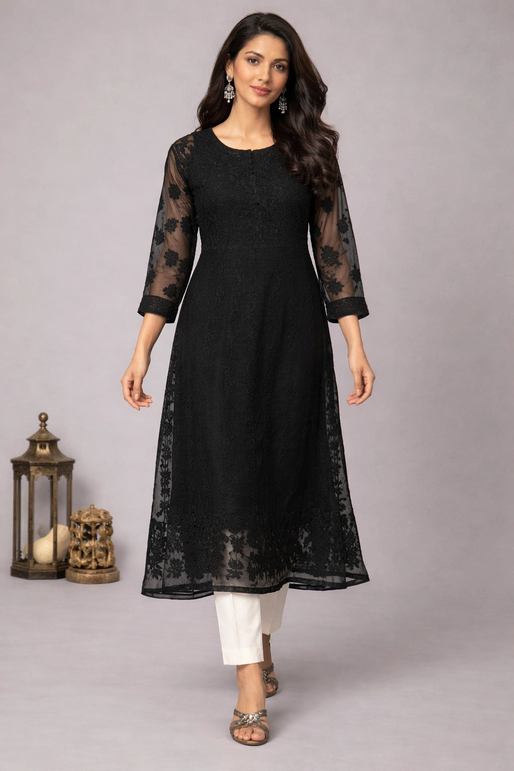 Woman wearing a black kurta with sheer sleeves against a gray background