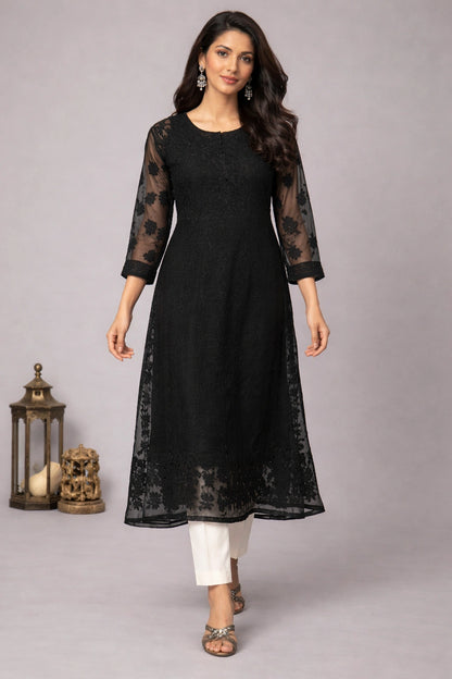 Woman wearing a black kurta with sheer sleeves against a gray background