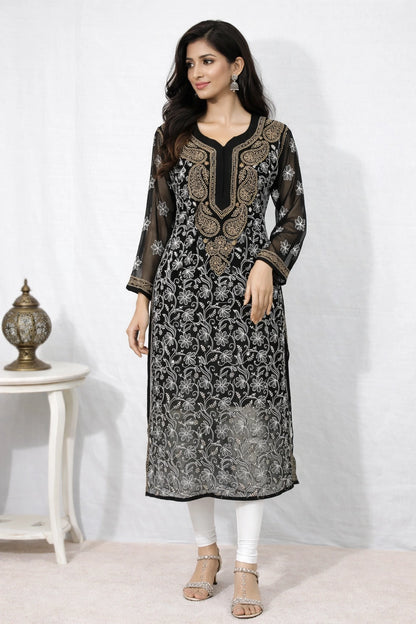 Woman wearing a black and gold embroidered kurta with white pants against a white background