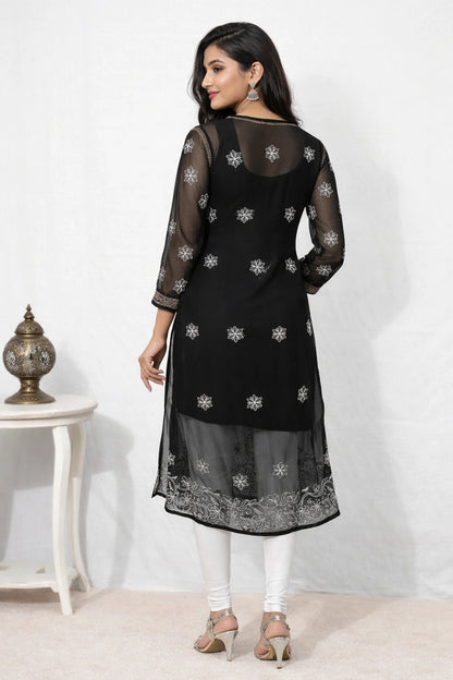 Woman wearing a black embroidered kurta with sheer sleeves against a white background