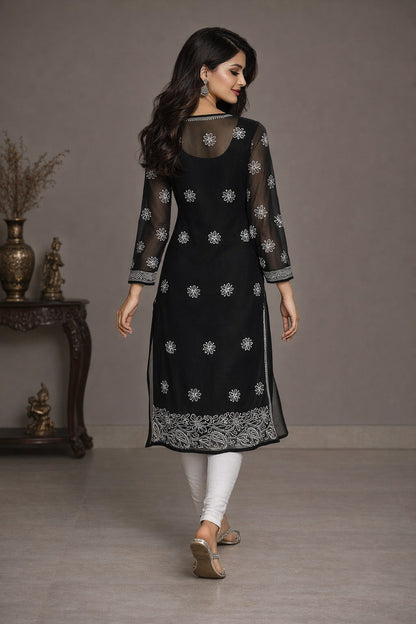 Woman wearing a black embroidered kurta with white pants in a minimalistic setting.