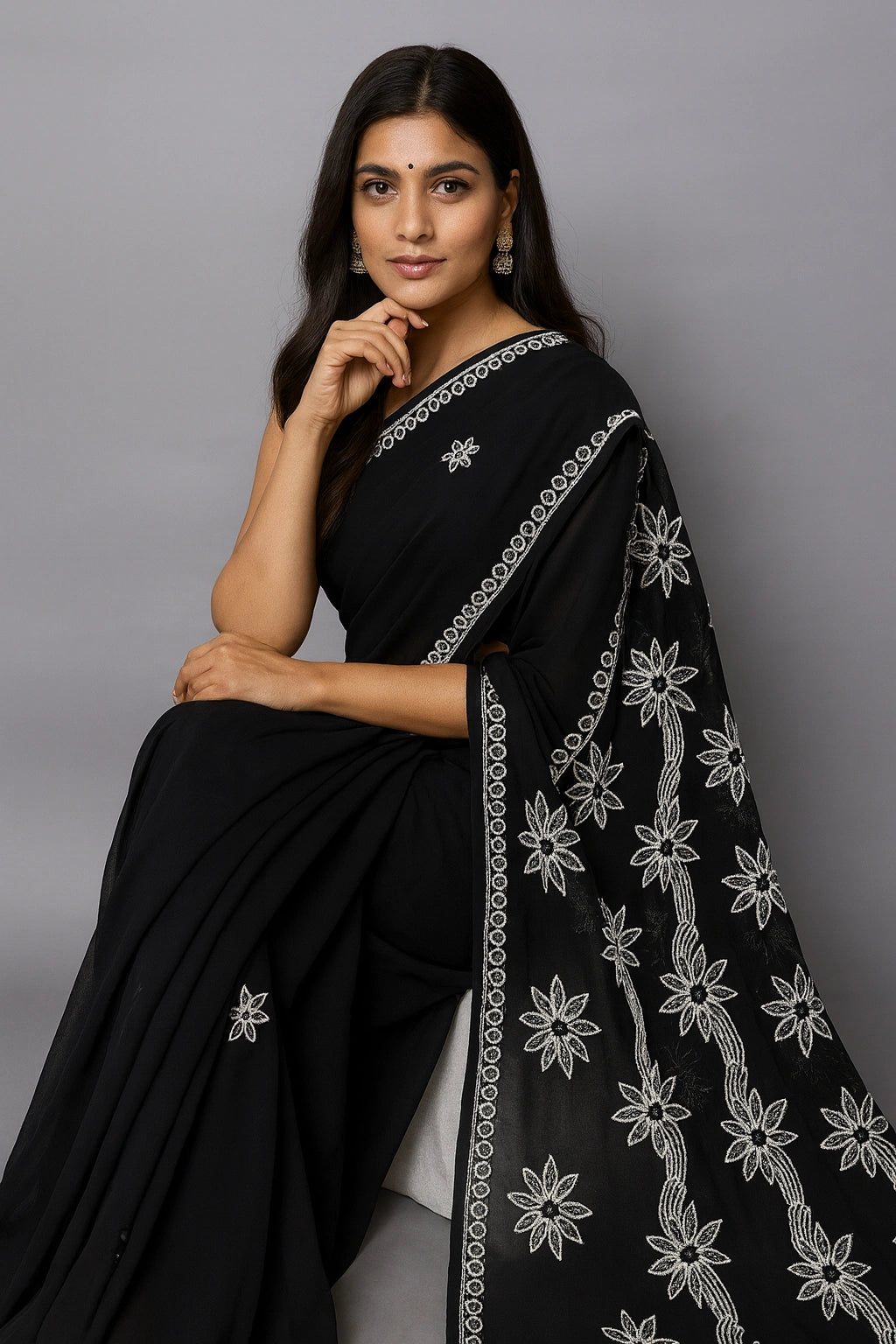 Woman wearing a lucknowi chikankari black saree with white floral patterns on a gray background