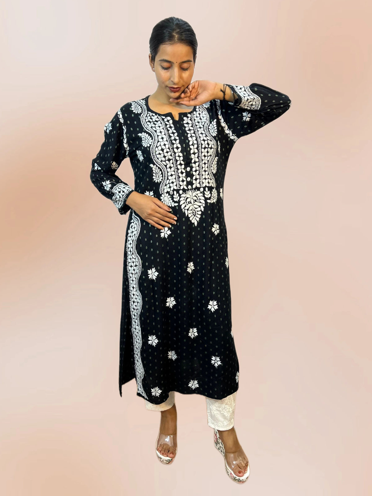 lucknowi chikankari Mannequin wearing a black and white patterned dress in front of shelves filled with colorful fabric.