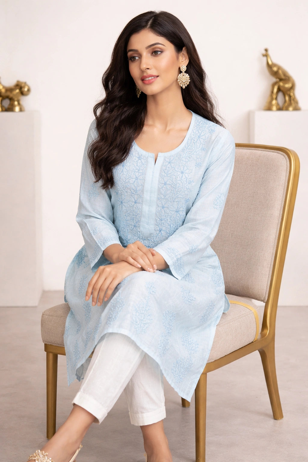lucknowi chikankari Woman wearing a light blue kurta with white pants sitting on a chair.