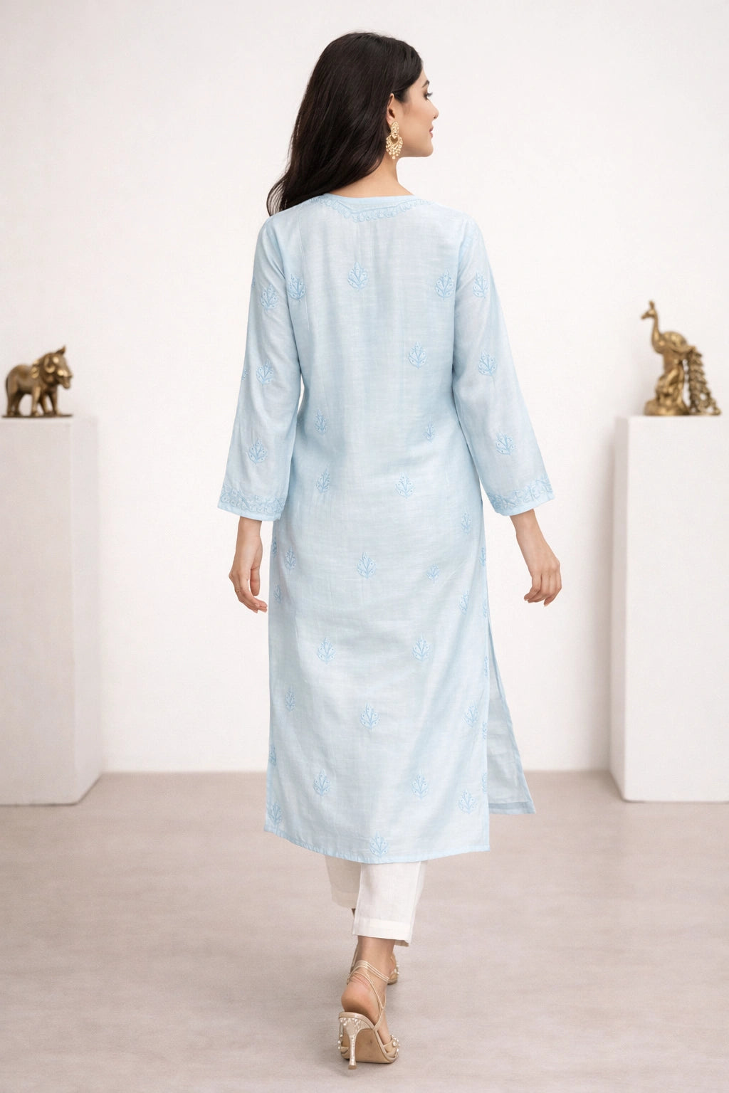 lucknowi chikankari Woman wearing a light blue kurta with white pants in a minimalistic setting.