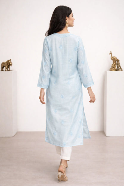 lucknowi chikankari Woman wearing a light blue kurta with white pants in a minimalistic setting.