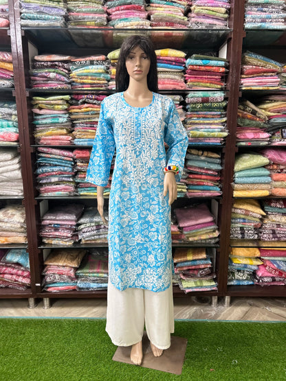 lucknowi chikankari Mannequin wearing a blue and white floral kurta with white pants in front of a colorful fabric background.