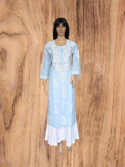 A light blue long kurta dress with white floral embroidery and a white lace hem, displayed on a female mannequin against a wood grain background.