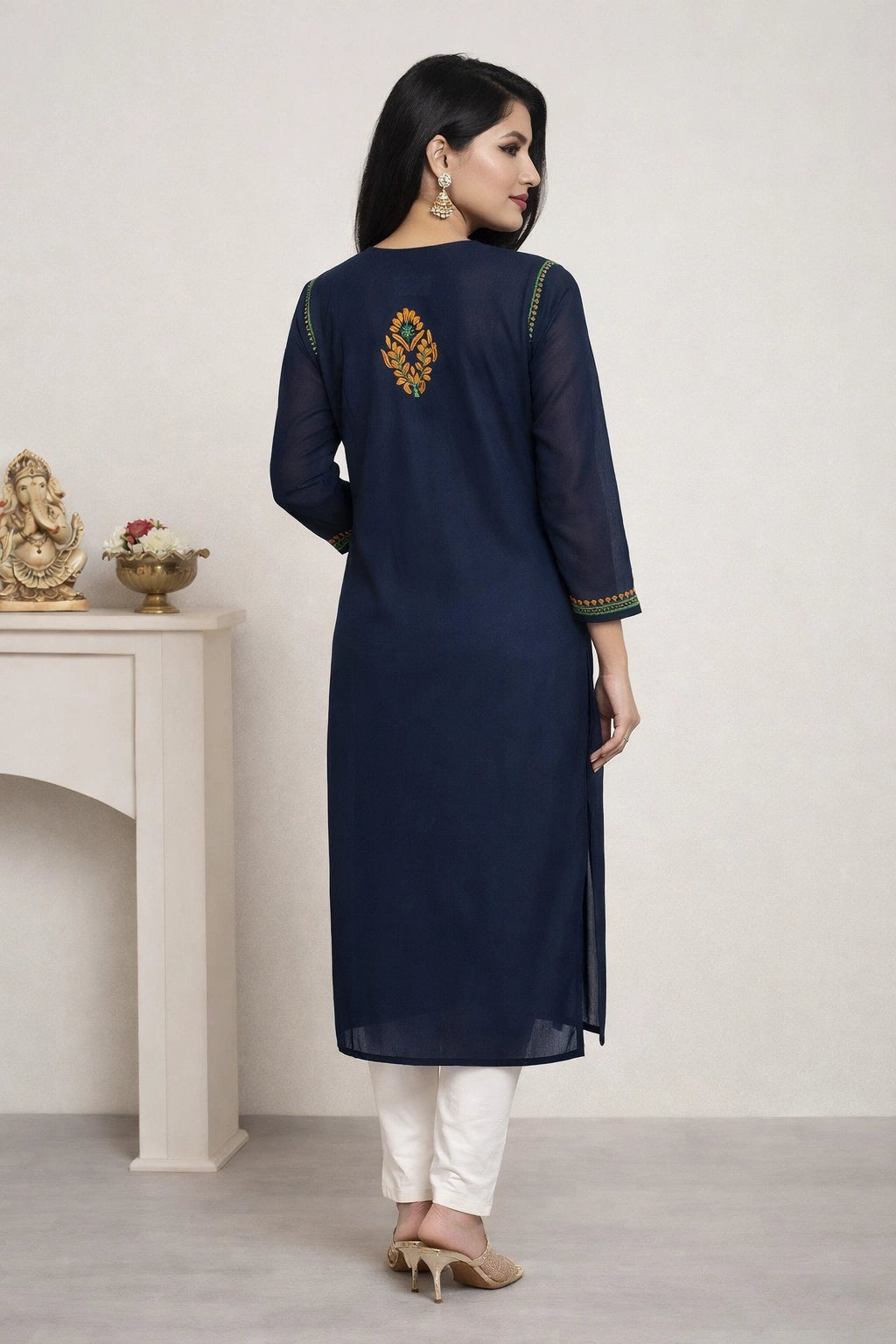Woman wearing a navy blue kurta with white pants in a minimalistic setting.