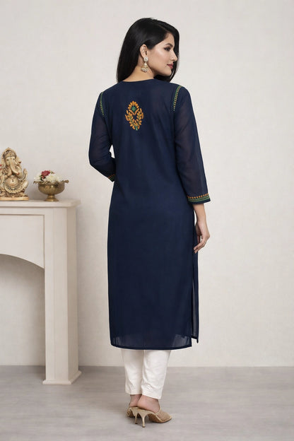 Woman wearing a navy blue kurta with white pants in a minimalistic setting.