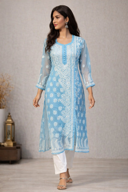 Woman wearing a light blue embroidered kurta with white pants against a neutral background