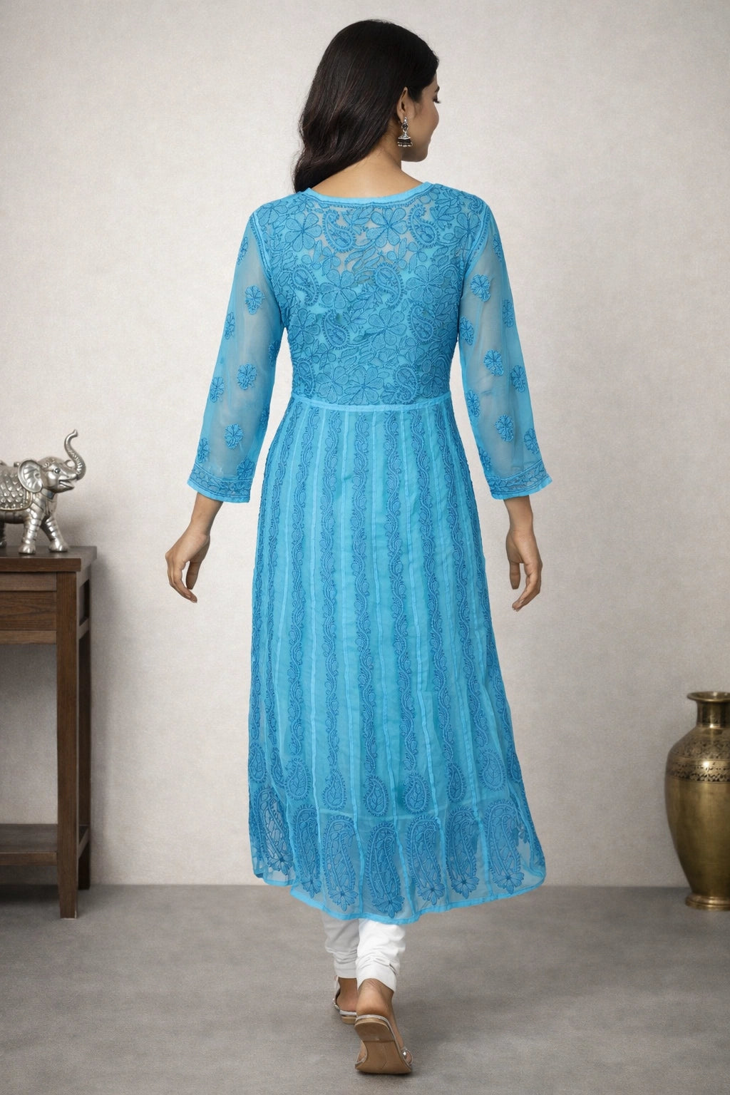 Woman wearing a blue lucknowi chikankari anarkali sitting on a chair.