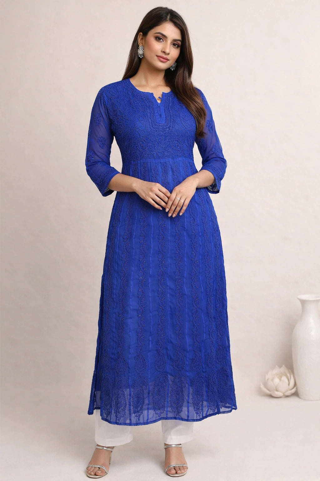 Woman wearing a blue lucknowi chikankari anarkali sitting on a chair.