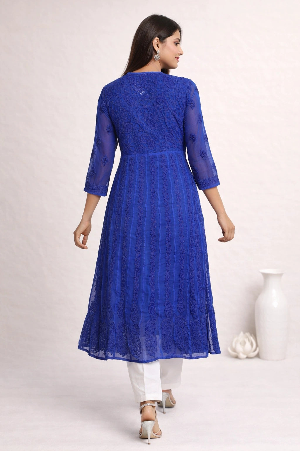 Woman wearing a blue lucknowi chikankari anarkali sitting on a chair.