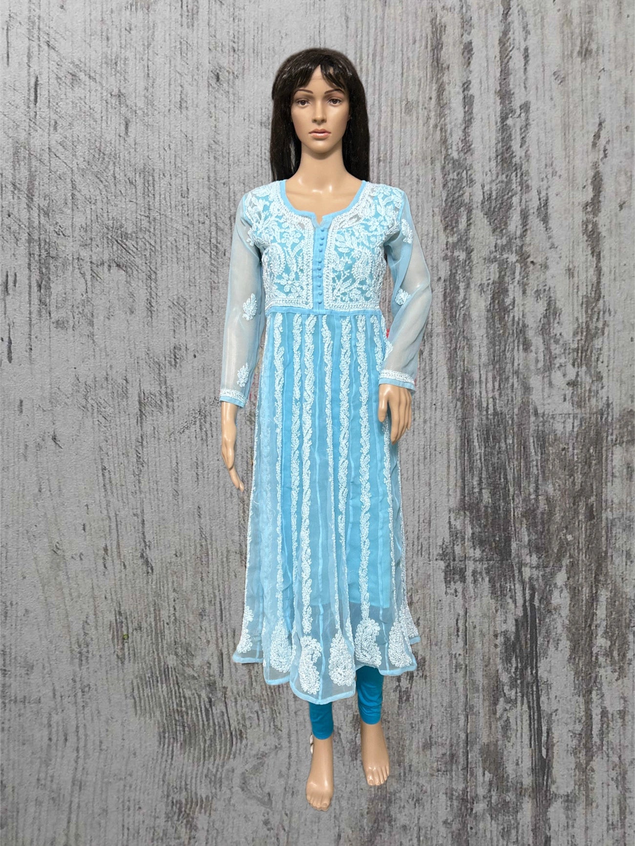 Mannequin wearing a light blue embroidered dress on a textured gray background