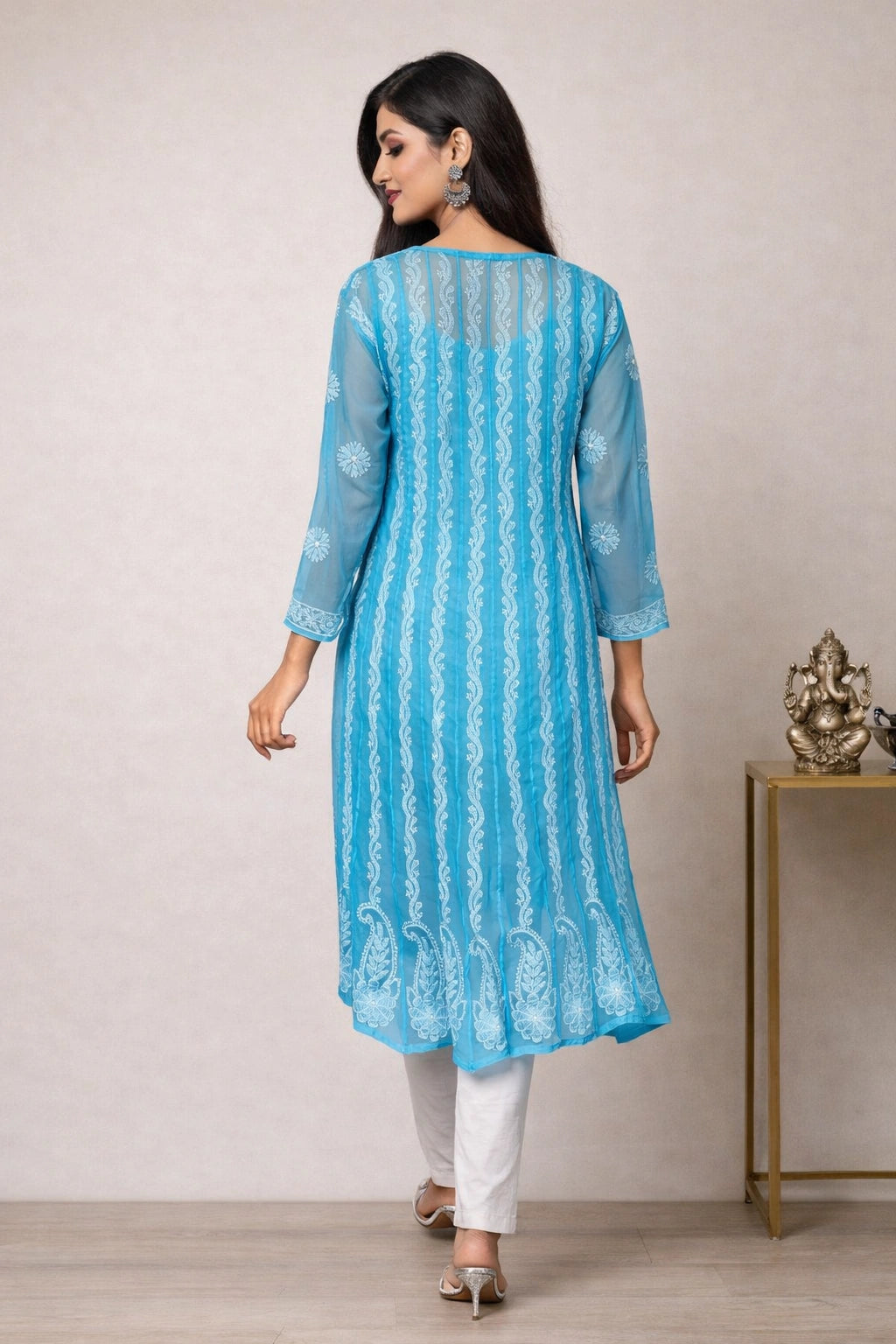 Woman wearing a blue lucknowi chikankari anarkali sitting on a chair.