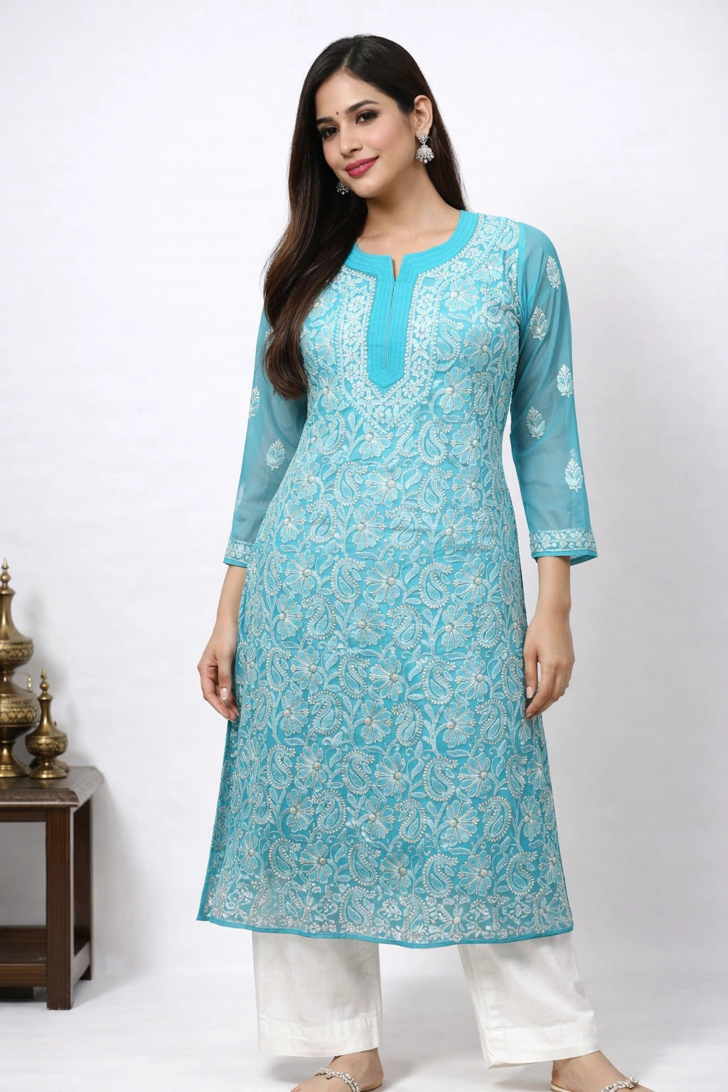 Woman wearing a light blue embroidered kurta with white pants on a white background