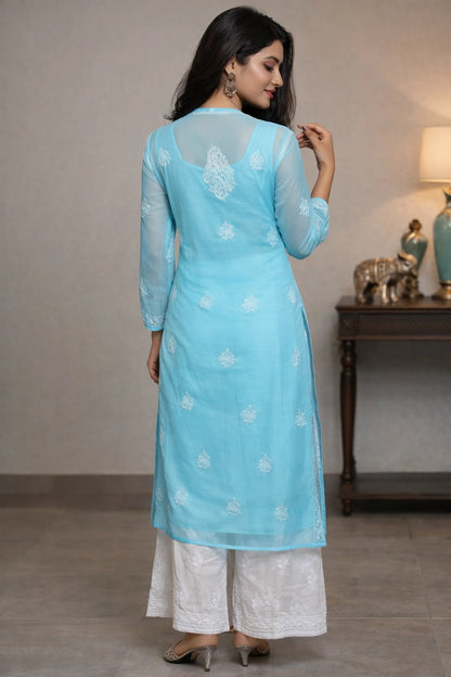 Woman wearing a light blue kurta with white patterns in a room setting.