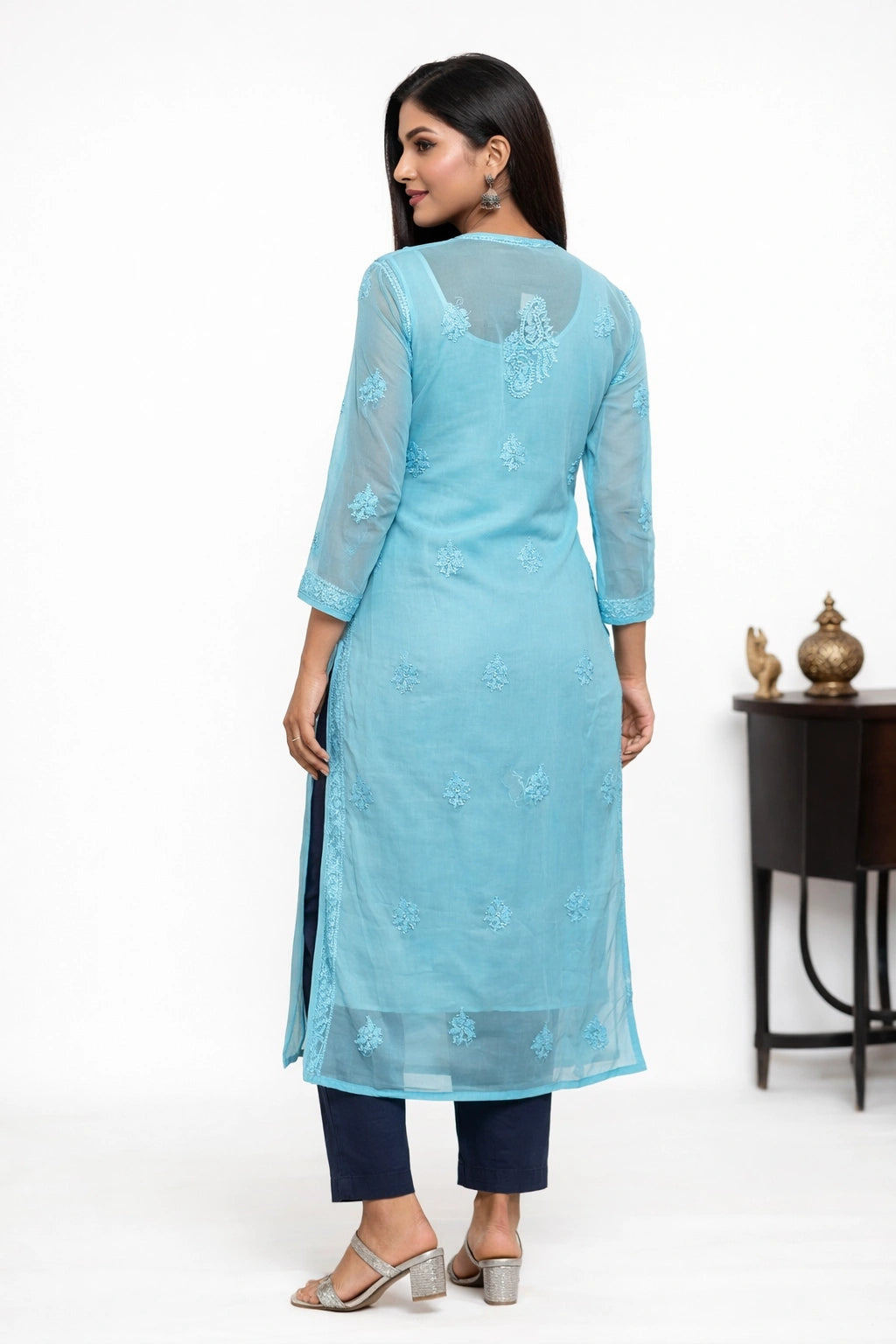 Woman wearing a light blue embroidered kurta with navy pants on a white background