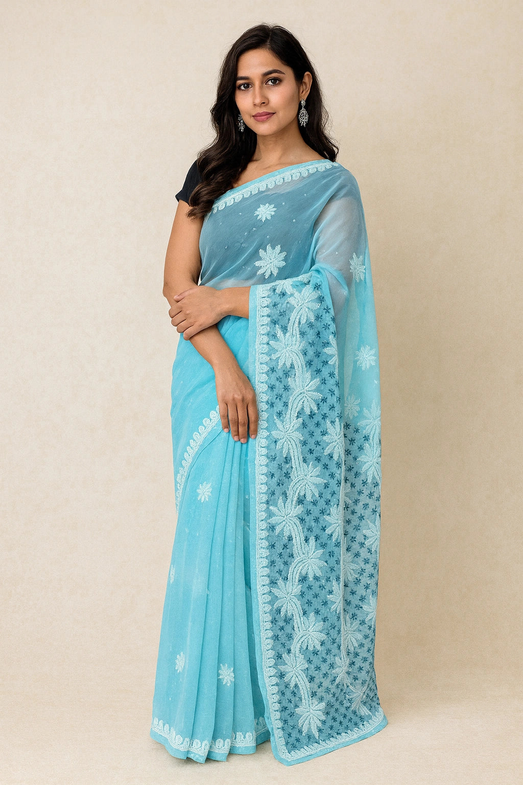 Woman wearing a lucknowi chikankari light blue saree with white floral patterns on a beige background