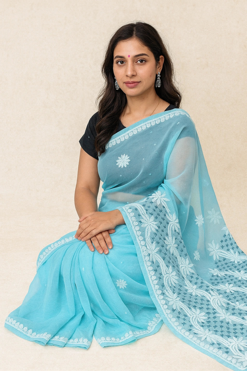 Woman wearing a light blue saree with white embroidery on a beige background