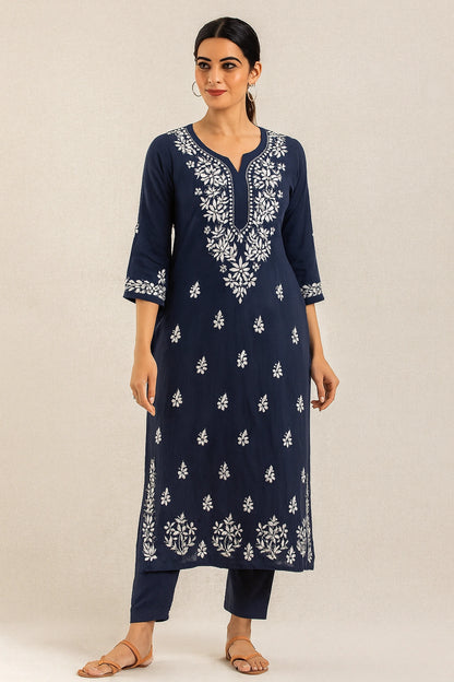 Woman wearing a navy blue kurta with white embroidery on a beige background