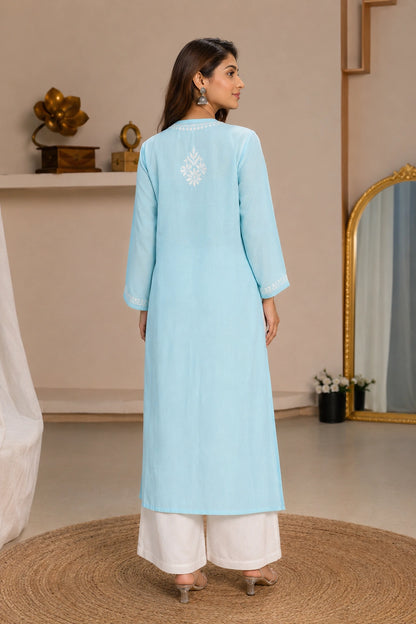 Woman wearing a blue embroidered dress against a beige background