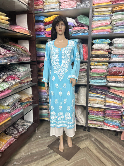 Mannequin wearing a blue embroidered dress in a fabric store with shelves of colorful fabrics.