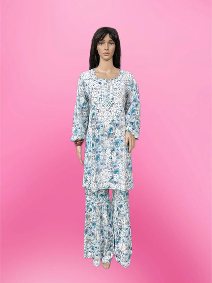Lucknowi chikankari A mannequin wearing a long-sleeve white kurta and matching wide-leg pants set with a blue floral pattern, set against a solid pink background.