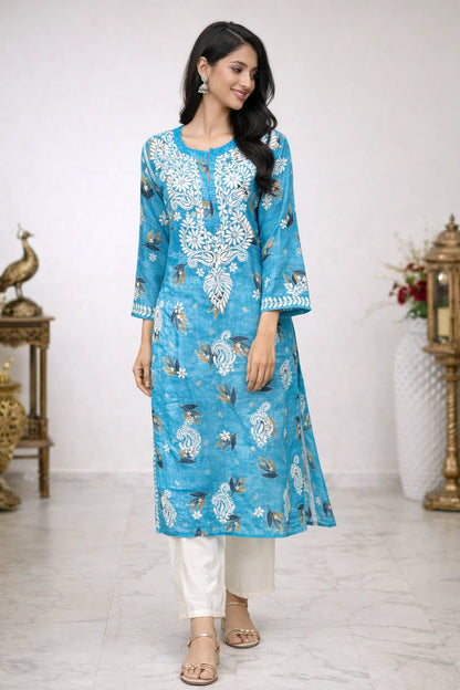 Woman wearing a blue floral kurta with white pants in a decorated room.
