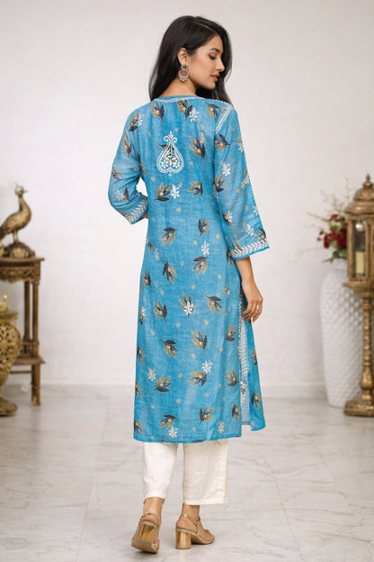 Woman wearing a blue embroidered kurta with white pants in a decorated room.