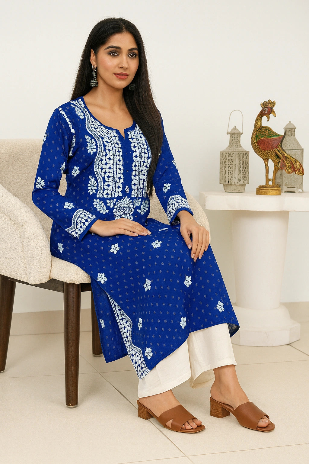 lucknowi chikankari Woman wearing a blue and white traditional outfit sitting on a chair.